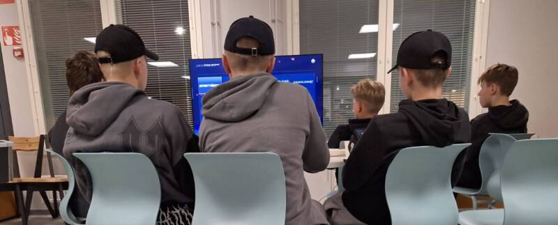 Nuoria pelaamassa PlayStationilla nuorisotiloilla.