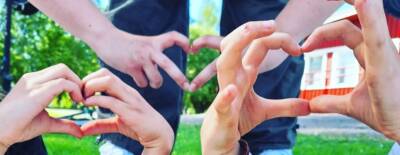 Nuorten tekemiä sydämen muotoisia käsimerkkejä.