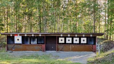 ampumataulut katoksessa, joiden takana metsää.